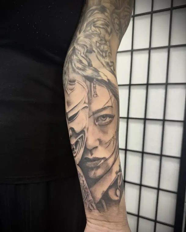A forearm sleeve: a woman’s face half-hidden behind a traditional Japanese mask, in black and grey.