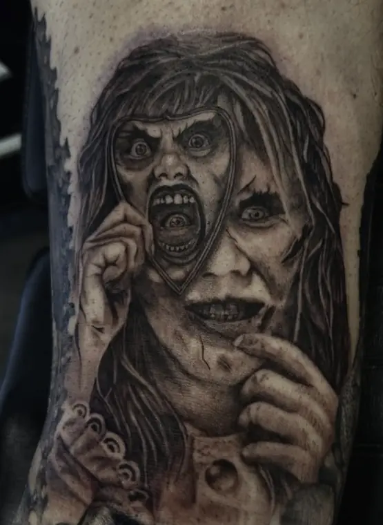 A horror-film portrait in black and grey realism on the upper arm.