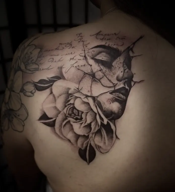 A rose and a woman’s eyes and lips over handwritten script, across the shoulder blade.